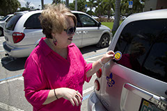 Woman placing the Yellow Dot decal on her car.